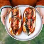Brats, peppers, and onions on a silver camping plate.