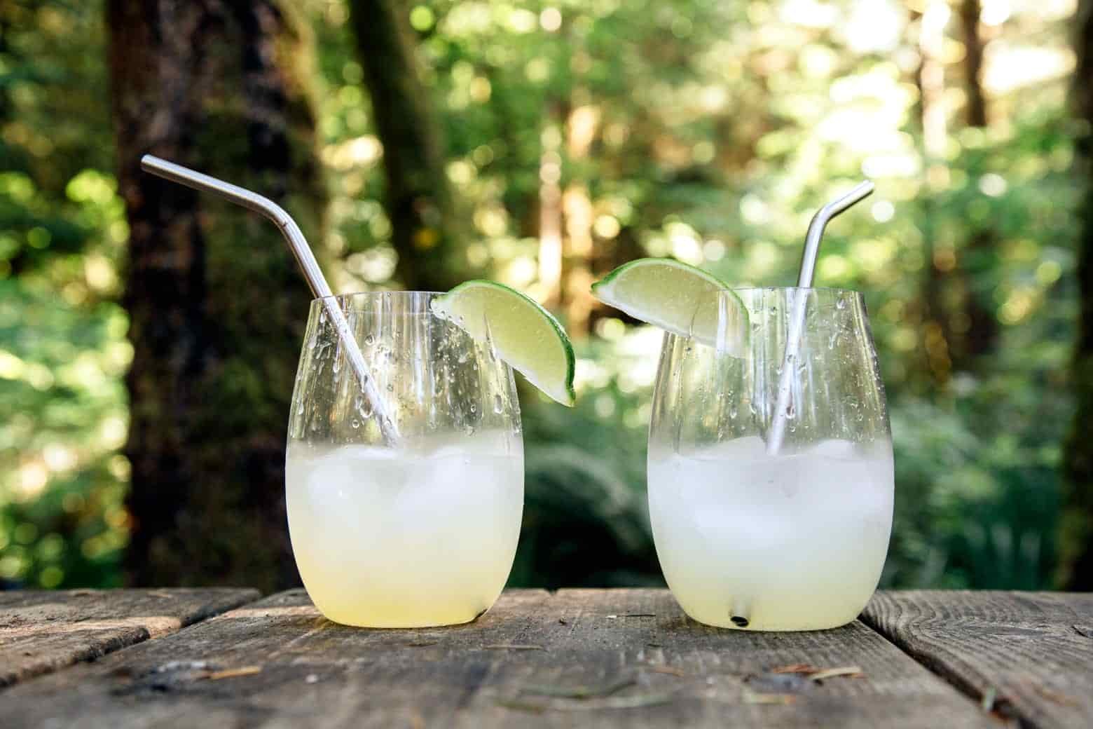 Two glasses of canchanchara on a camp table with greenery in the background